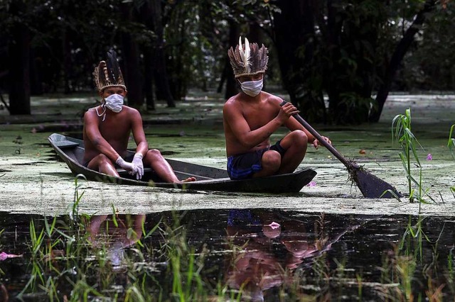 Zwei Indios mit Mundschutz paddeln auf... Corona-Pandemie besonders betroffen.   | Foto: RICARDO OLIVEIRA (AFP)