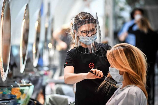 Eine Friseurin mit Gesichtsschutz bedi...Kundin mit Mundschutz im Friseursalon.  | Foto: Claudio Furlan (dpa)