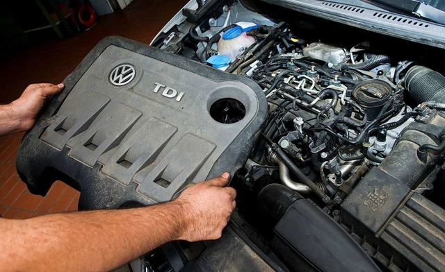 Ein KFZ-Servicetechniker in einer Auto... betroffenen Dieselmotor vom Typ EA189  | Foto: Julian Stratenschulte (dpa)