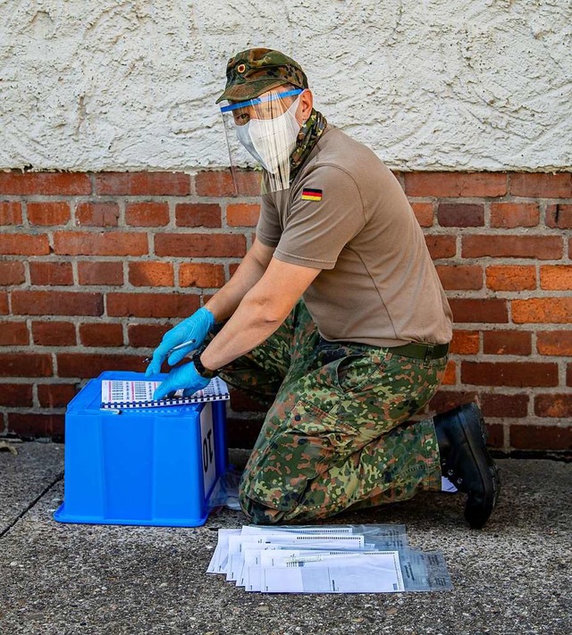 Ein Soldat der Bundeswehr dokumentiert...Hause in ihrer Quarantne aufzusuchen.  | Foto: David Inderlied (dpa)