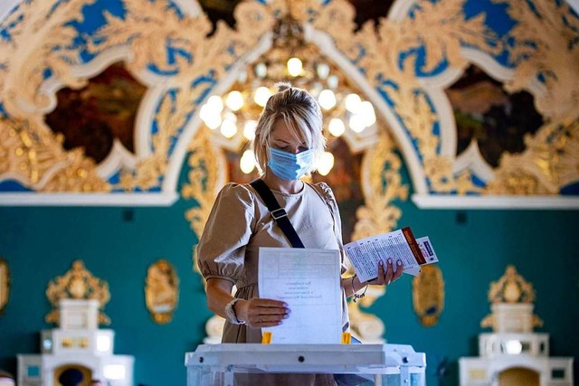 Eine Whlerin, die einen Mundschutz un...auer Kasaner Bahnhof in eine Wahlurne.  | Foto: Alexander Zemlianichenko (dpa)