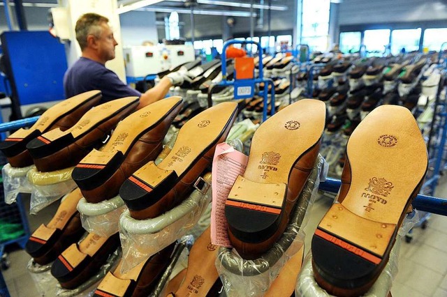 Ein Mitarbeiter der Schuhfabrik Lloyd ...llte Schuhe auf Transportgestellen ab.  | Foto: Ingo Wagner (dpa)