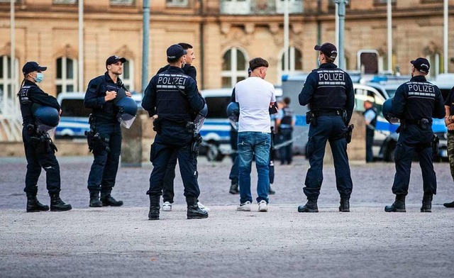 Polizisten bei einer Personenkontrolle auf dem Stuttgarter Schlossplatz.  | Foto: Christoph Schmidt (dpa)