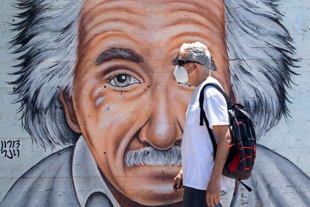 In Tel Aviv in Israel geht ein Mann mi...ild vorbei, das Albert Einstein zeigt.  | Foto: Sebastian Scheiner (dpa)
