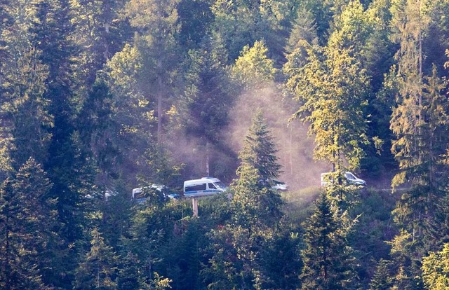 Fahrzeuge der Polizei fahren durch den Wald in der Nhe von Oppenau.  | Foto: Philipp von Ditfurth (dpa)