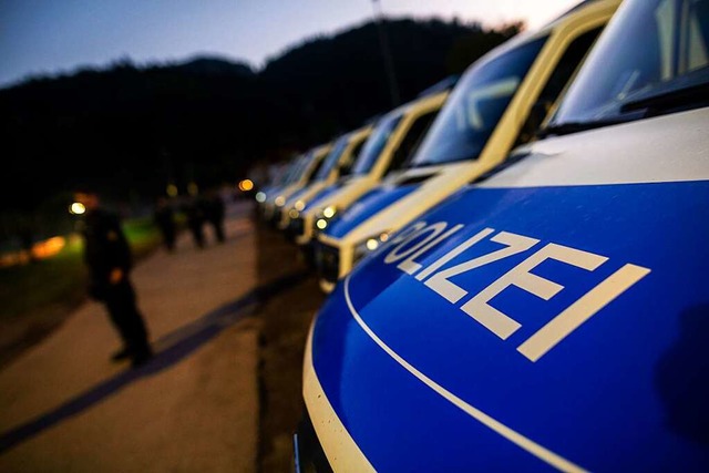 Polizisten und Polizeifahrzeuge stehen...der der Polizei als Sammelpunkt dient.  | Foto: Philipp von Ditfurth (dpa)