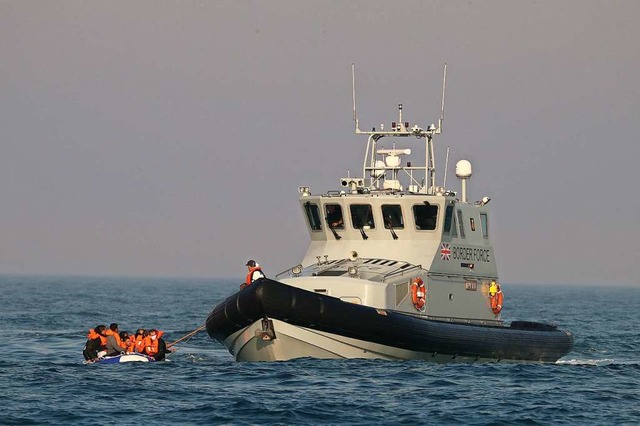 Ein Beamter des britischen Grenzschutz...cht mit einer Gruppe von Flchtlingen.  | Foto: Gareth Fuller (dpa)