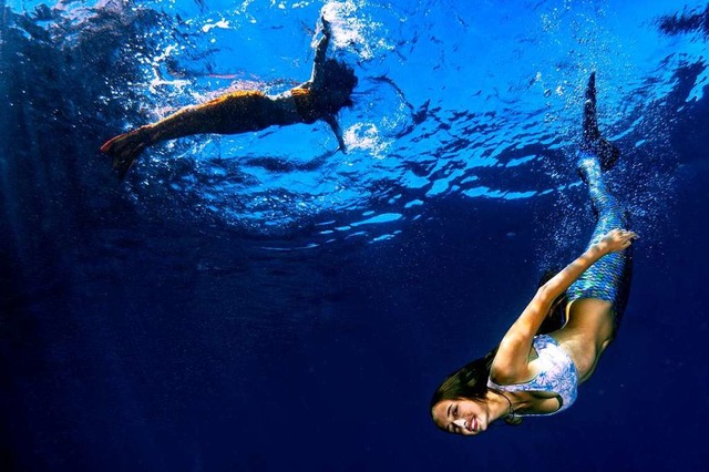 Zwei junge Frauen schwimmen mit Meerjungfrauenschwnzen durchs Wasser.  | Foto: Andrea Izzotti  (stock.adobe.com)