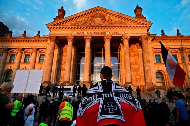 Ein Demonstrant mit einer Flagge in de...vor dem Berliner Reichstag am Samstag.  | Foto: JOHN MACDOUGALL (AFP)