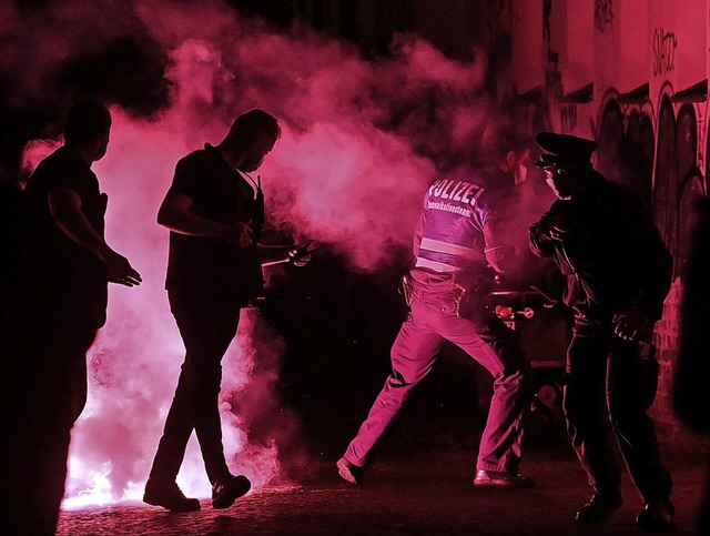 Polizisten fliehen am Samstag bei einer Demo in Leipzig vor Pyrotechnik.  | Foto: Hendrik Schmidt (dpa)