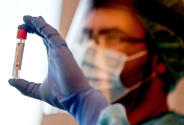 Ein Arzt hlt  einen Abstrich fr einen Coronavirus-Test.  | Foto: Britta Pedersen (dpa)
