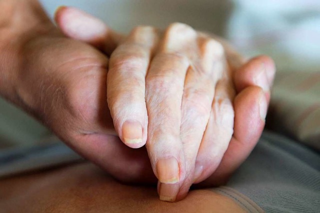 Ein Altenpfleger hlt in einem Pflegeheim die Hand einer Frau.  | Foto: Sebastian Kahnert (dpa)
