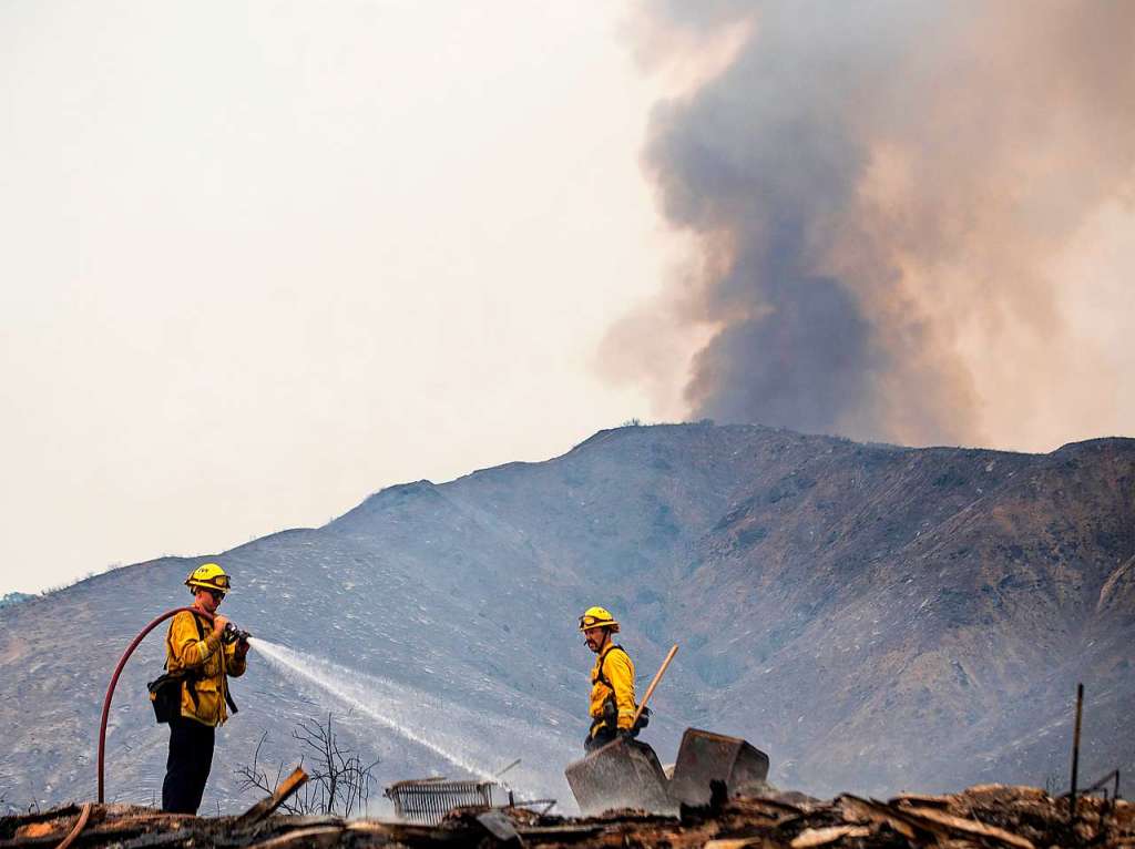 Feuerwehrleute lschen heie Stellen an einem Bauwerk, das in der Nhe von Yucaipa durch den El Dorado Waldbrand zerstrt wurde.