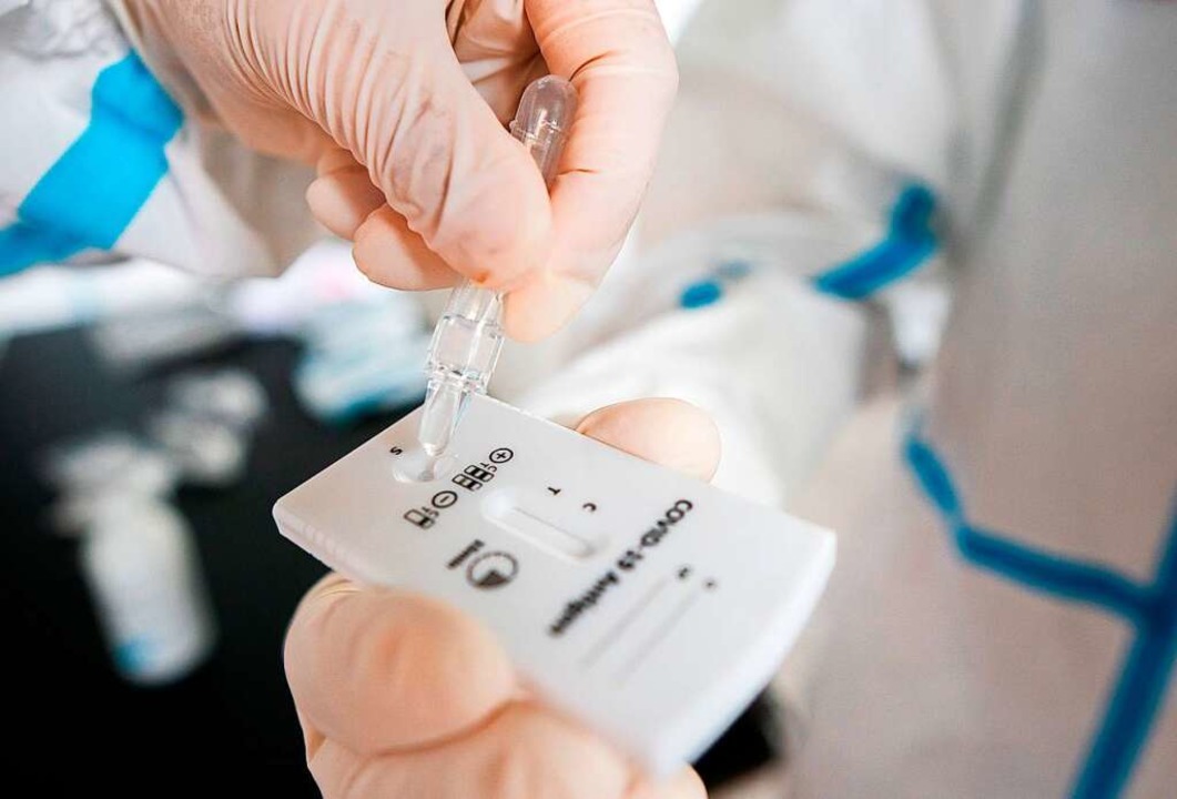 Ein Test auf Antigene gegen Covid-19 wertet ein medizinischer Mitarbeiter aus.  | Foto: GEORG HOCHMUTH (AFP)