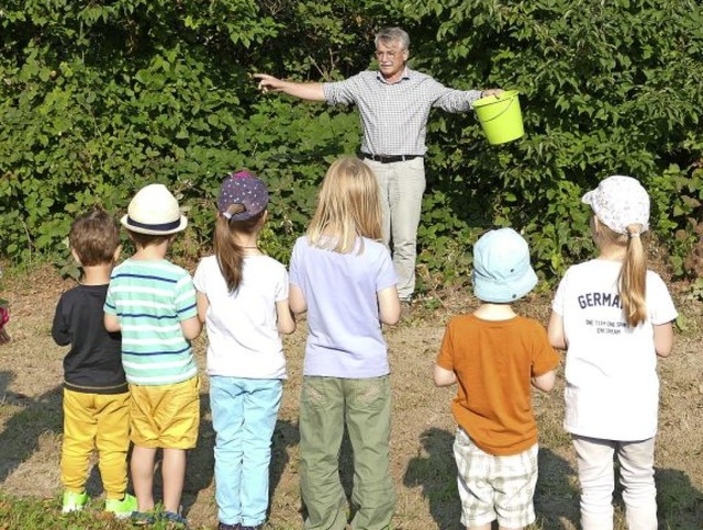 Manfred Kraft erklrt den Kindern, wie...eter groen Flche verstreuen sollen.   | Foto: Savanna Cosma