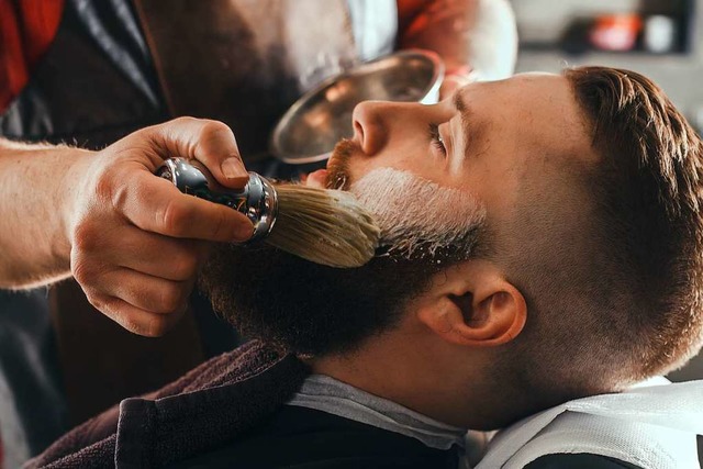 Mit Rasierpinsel und Seifenschaum wird ein Mann von einem Barbier rasiert.   | Foto: karmaknight  (stock.adobe.com)