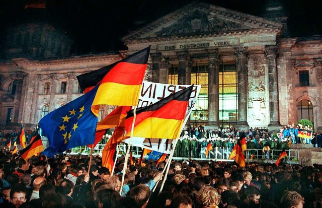 Menschen feiern in der Nacht zum 03.10.1990 vor dem Reichstagsgebude in Berlin.  | Foto: Wolfgang Kumm (dpa)