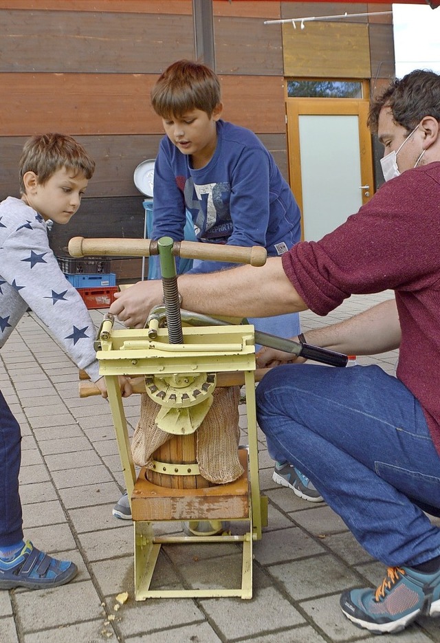 Malte Lindemann hilft Lucas (links) und Bastian beim Mosten an der Trotte.  | Foto: Horatio Gollin