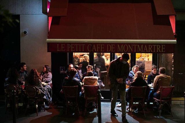 Besucher sitzen auf einer Cafterrasse in Paris.  | Foto: Lewis Joly (dpa)