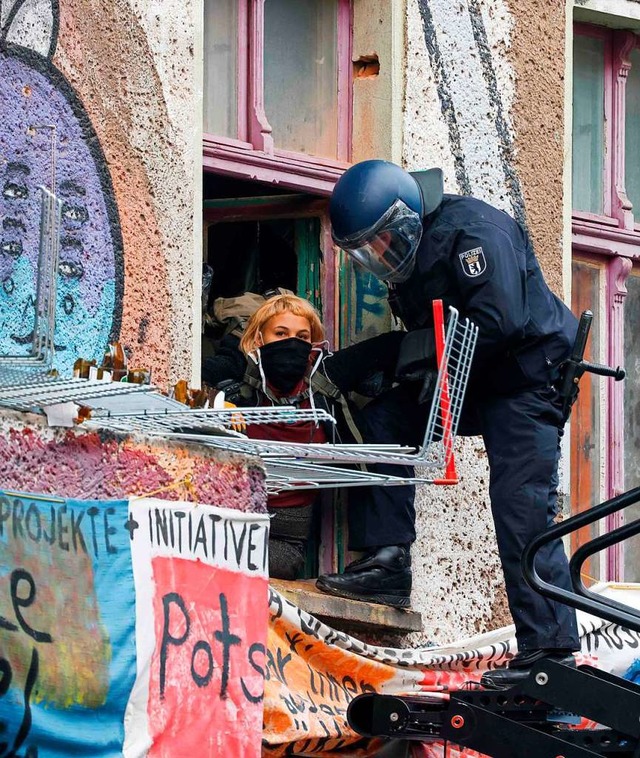 Ein Polizist fhrt eine Besetzerin aus dem Haus.  | Foto: ODD ANDERSEN (AFP)