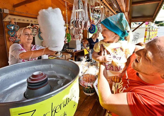 Ein Kind bekommt leckere Zuckerwatte am Stand eines Schaustellers.  | Foto: Michael Bamberger