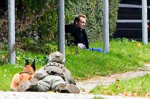 Ein Polizist liegt neben einem Polizei...einem Straenrand auf dem Boden sitzt.  | Foto: Nils Meilvang (dpa)