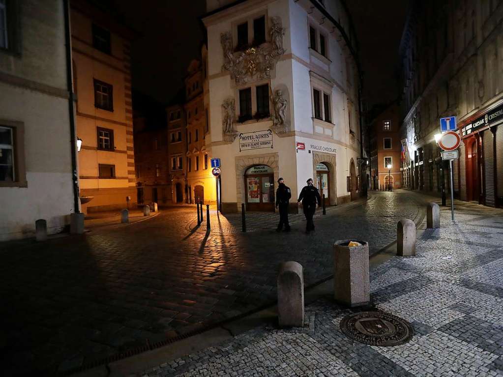 Polizisten  patrouillieren  auf einer leeren Strae in Prag nach Beginn der nchtlichen Ausgangssperre.