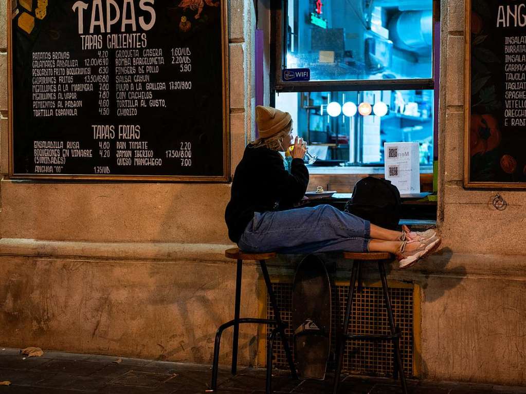 Eine Frau trinkt vor einer Bar in Barcelona.