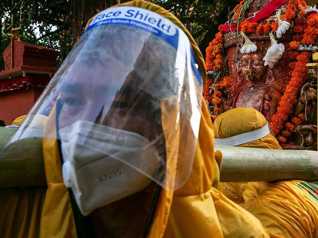 Nepalesische Glubige haben Visiere und Mund-Nasen-Bedeckungen aufgesetzt.