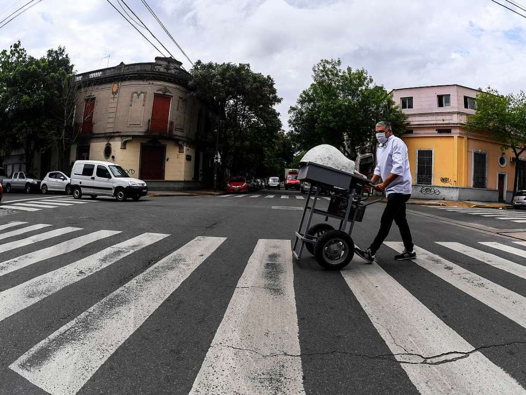 Ein Mann schiebt einen Wagen  eine Strae in Buenos Aires hinunter.