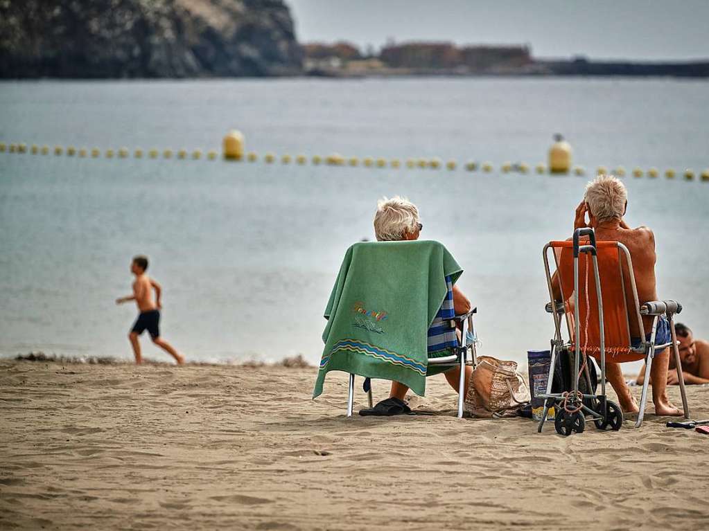 Touristen genieen die Sonne am Strand  auf den Kanaren.