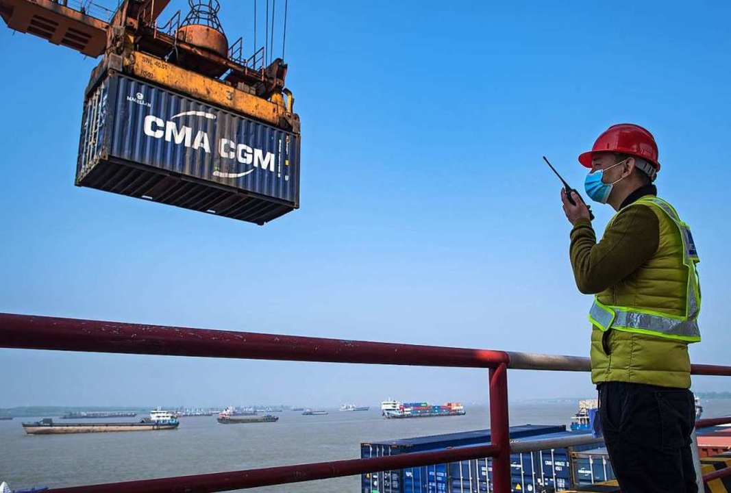 Ein Mann rangiert Container für die We...ung in einer Logistikstation in China.  | Foto: Xiao Yijiu (dpa)
