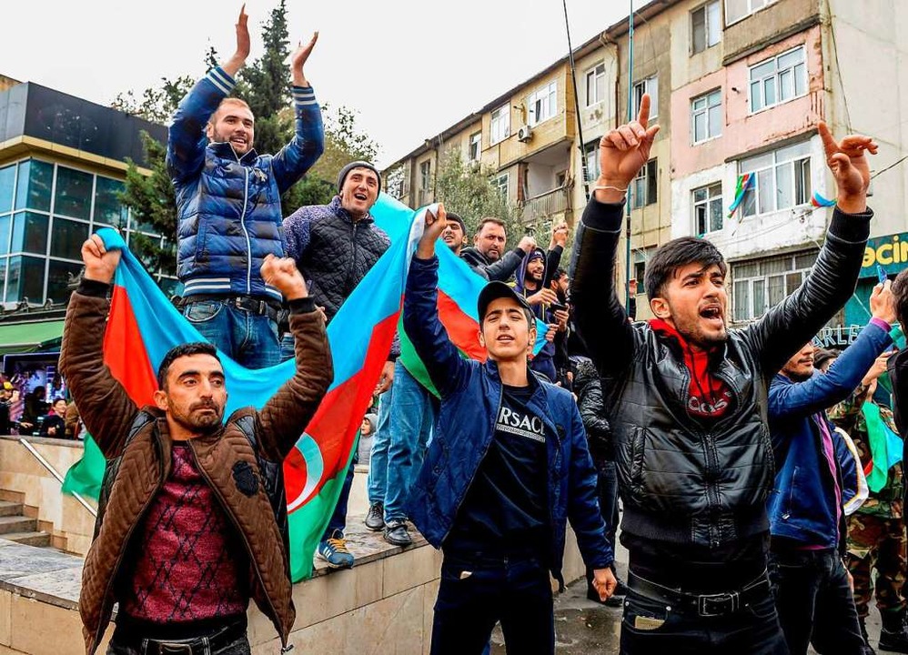 Menschen feiern in Baku mit der aserbaidschanischen Flagge.  | Foto: TOFIK BABAYEV (AFP)