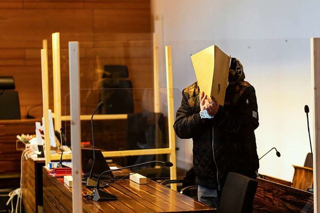 Der Angeklagte verbirgt sein Gesicht hinter Gerichtsakten.  | Foto: Philipp von Ditfurth (dpa)