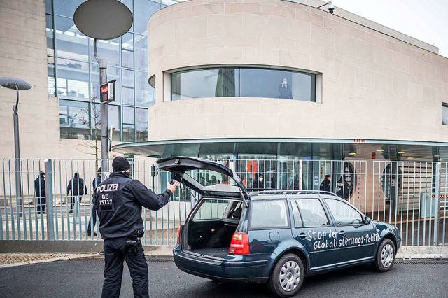 Ein Polizist steht vor dem Kanzleramt ...ren war, und blickt in den Kofferraum.  | Foto: Michael Kappeler (dpa)