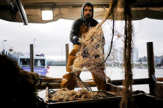 Ein Fischer reinigt sein Netz im Hafen von Boulogne-sur-Mer.  | Foto: Thibault Camus (dpa)