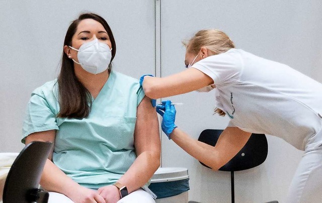 Christine Helbig (l), Pflegekraft am K...kam direkt von der Arbeit zur Impfung.  | Foto: Marijan Murat (dpa)