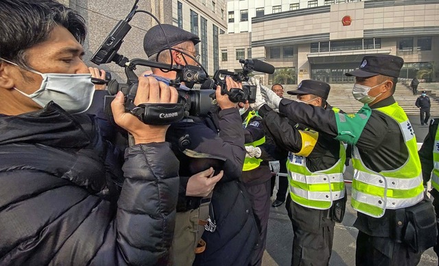 Polizisten behindern Fernsehjournalist... vor dem Gerichtsgebude in Schanghai.  | Foto: LEO RAMIREZ (AFP)