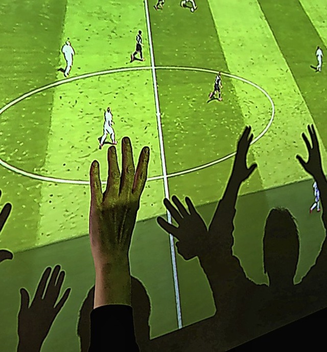 Freunde im Wohnzimmer schauen das mit ...die Wand geworfene Spiel gemeinsam an.  | Foto: Karl-Josef Hildenbrand (dpa)