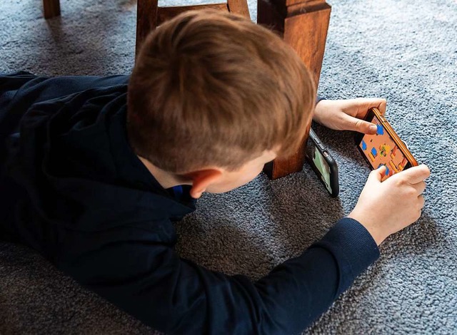 Ein Junge spielt ein Videospiel auf de... einem zweiten Handy zu seinem Freund.  | Foto: Robert Michael (dpa)