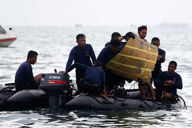 Taucher der indonesischen Marine ziehe...ugzeugteil aus dem Wasser in ein Boot.  | Foto: Achmad Ibrahim (dpa)