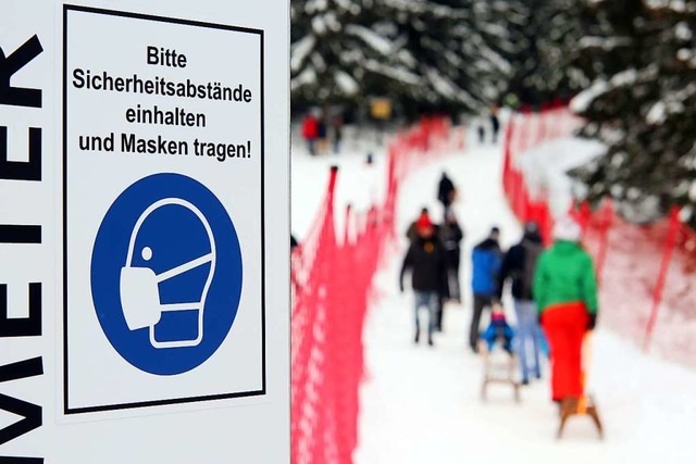 Ein Schild mit dem Hinweis zur Maskenpflicht steht am Eingang einer Skiloipe.  | Foto: Matthias Bein (dpa)