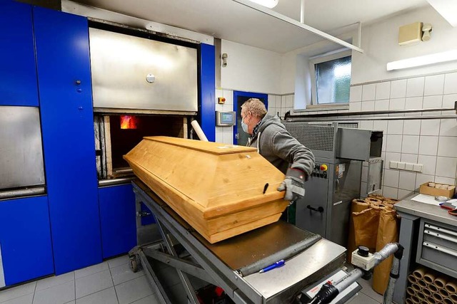 Ein Mitarbeiter schiebt einen Sarg in ...fenanlage des Freiburger Krematoriums.  | Foto: Ingo Schneider