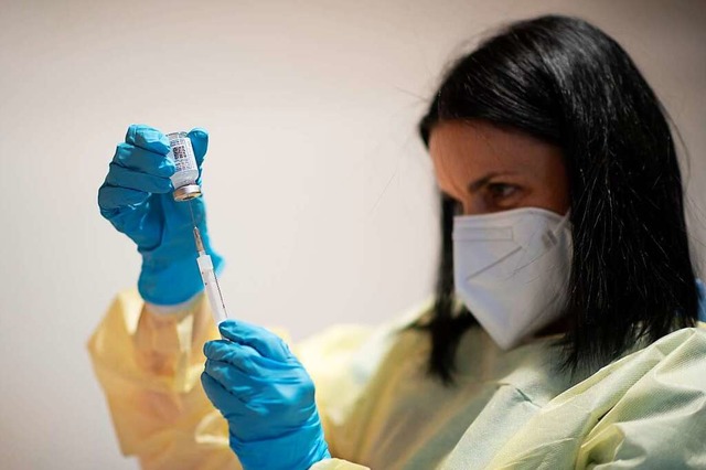 Eine Mitarbeiterin mit Mund-Nasen-Schutz bereitet eine Corona-Impfung vor.  | Foto: Gian Ehrenzeller (dpa)