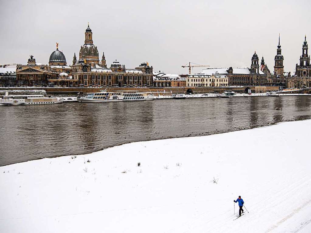 Sachsen, Dresden: Ein Mann luft mit Langlaufski am verschneiten Elbufer gegenber der Altstadt mit der Kuppel der Kunstakademie (l-r), der Frauenkirche, dem Stndehaus, dem Georgentor, dem Hausmannsturm und der Hofkirche entlang.