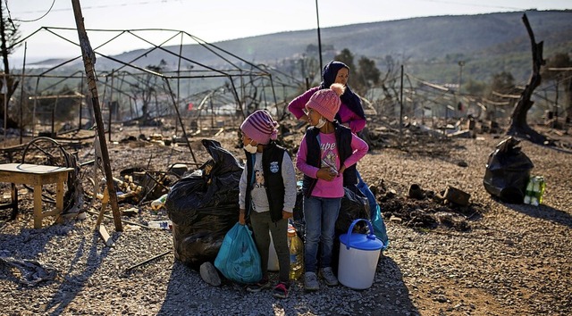 Eine Familie steht im September im ausgebrannten Flchtlingslager Moria  | Foto: Socrates Baltagiannis (dpa)