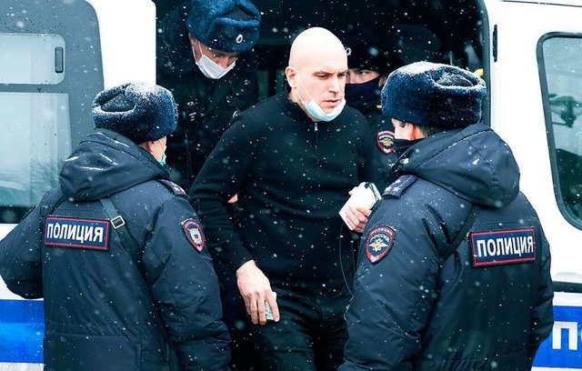 Ein Mann steht von Polizisten umgeben ...eiauto, nachdem er festgenommen wurde.  | Foto: Victor Berezkin (dpa)