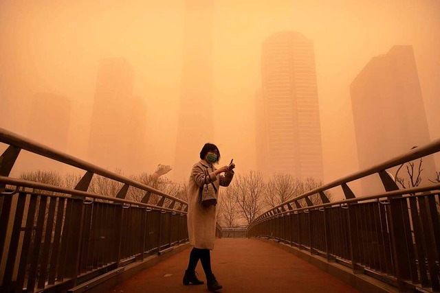 Peking: Eine Frau geht whrend des mor...elt und die Luftqualitt ist schlecht.  | Foto: Mark Schiefelbein (dpa)