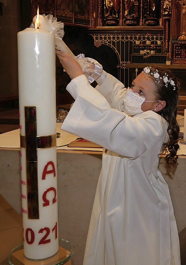 Elina zndet ihre Kommunionskerze an der Osterkerze im Mnster an.  | Foto: Eva Korinth