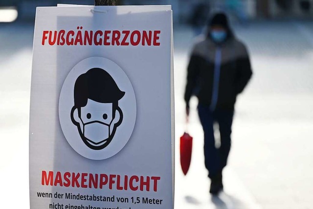 Ein Schild weist auf die Maskenpflicht in der Fugngerzone hin.  | Foto: Marijan Murat (dpa)